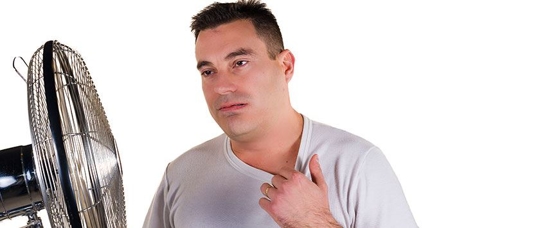 man next to fan sweating